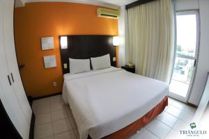 sypialnia z dużym białym łóżkiem w pokoju w obiekcie Triângulo Apart Hotel w mieście Vitória