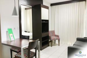 a living room with a table and chairs in a room at Triângulo Apart Hotel in Vitória +35 photos