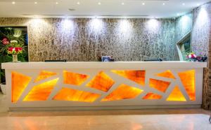 a reception desk in a hotel lobby with orange and yellow artwork at Hotel Rockdale in Visakhapatnam