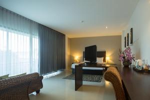 a living room with a television on a desk with a bed at Wilacha Chiang Rai in Chiang Rai