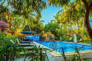 a swimming pool with palm trees around it at Sea View Resort in Patnem