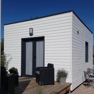 um edifício branco com uma porta preta num convés em Au Cap Norwoe em Saint-Quentin-en-Tourmont