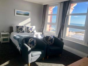 a bedroom with a bed and a chair and windows at The Blenheim in Dawlish