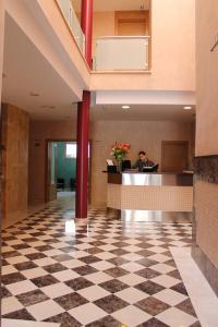 a man sitting at a desk in a lobby with a checkered floor at Hotel Carmen in La Cala de Mijas