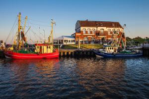 3 Boote sind an einem Dock im Wasser angedockt. in der Unterkunft Gud Jard Lodge Nr 23 - Design-Ferienhaus mit exklusiver Ausstattung in Pellworm