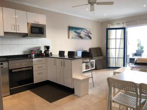 a kitchen with white cabinets and a table and a dining room at Apartment Layla in Puerto del Carmen