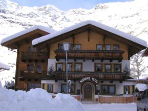 a large wooden building with snow covered mountains at Residence Texel in Pfelders