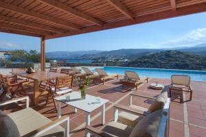 a patio with tables and chairs and a pool at Miramare Resort & Spa in Agios Nikolaos