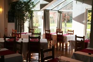 ein Restaurant mit Tischen und Stühlen und einem großen Fenster in der Unterkunft Hôtel Eco Relais - Pau Nord in Lons
