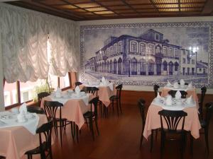 une salle à manger avec des tables et des chaises et un tableau mural dans l'établissement Luso Brasileiro, à Póvoa de Varzim