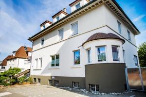 ein weißes Gebäude mit braunem Dach in der Unterkunft Hotel am Römerplatz in Ulm