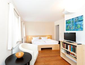 a white bedroom with a bed and a tv at Fährmannhaus in Bad Schandau