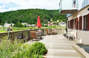 einen hölzernen Gehweg mit Stühlen und einem roten Regenschirm in der Unterkunft Fährmannhaus in Bad Schandau