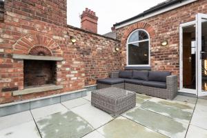 a patio with a couch and a brick wall at The Penthouse Sale in Sale