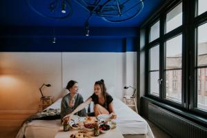 mężczyzna i kobieta siedzący na łóżku z jedzeniem w obiekcie Bike'UP Wrocław we Wrocławiu