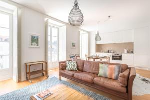 ein Wohnzimmer mit einem braunen Sofa und einer Küche in der Unterkunft Prime Lisbon - Mouraria in Lissabon