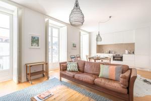 a living room with a brown couch and a kitchen at Prime Lisbon - Mouraria in Lisbon