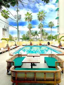 a pool with tables and chairs and palm trees at Broadmore Miami Beach in Miami Beach