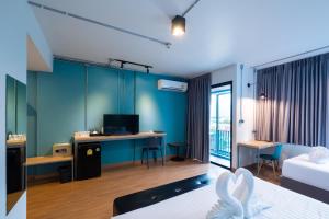 ein Hotelzimmer mit blauen Wänden, einem Bett und einem Schreibtisch in der Unterkunft S.22 Hotel Suratthani in Surat Thani