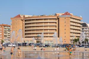- des personnes sur la plage en face d'un grand bâtiment dans l'établissement htop Royal Sun Suites #htopFun, à Santa Susanna