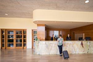 une femme avec une valise dans un aéroport avec des personnes dans l'établissement htop Royal Sun Suites #htopFun, à Santa Susanna