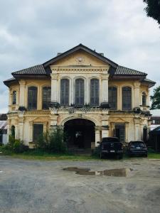 an old house with cars parked in front of it at Phuket Sunny Hostel in Phuket Town