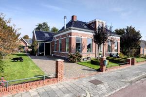 a large brick house with a black dog in front of it at De Strandkorf in Roodeschool