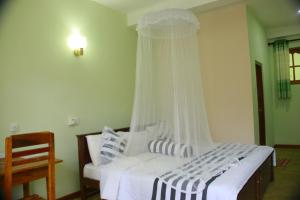 a bedroom with a white bed with a canopy at Dinaro Guest in Ella