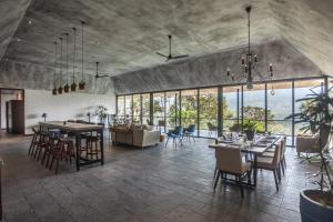 a dining room with tables and chairs and windows at Elakai in Munnar