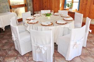 una sala da pranzo con tavolo e sedie bianche di Albergo Dei Pescatori a Piode