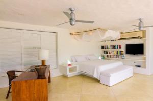 um quarto branco com uma cama e uma televisão em Villa Deluxe Los Cocos Baru em Barú
