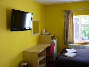 Habitación con escritorio y TV en la pared. en Acton Town Hotel, en Londres