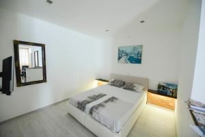 a white bedroom with a bed and a mirror at Apartment Citta Vecchia in Mostar