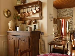 a kitchen with a wooden cabinet with pots and pans on the wall at LE TERTRE in La Feuillie