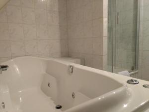 een badkamer met een wit bad en een douche bij B&B-Hotel de Joremeinshoeve in Kaatsheuvel
