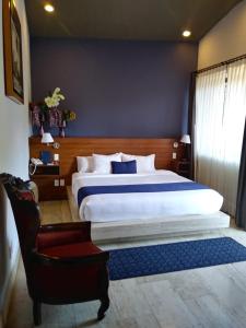 1 dormitorio con 1 cama grande y 1 silla en Araucaria Hotel Boutique, en Valle de Bravo