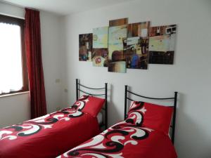 two beds with red pillows in a bedroom at Appartamento Morena in Malcesine