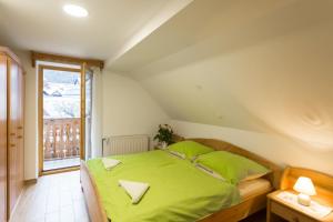 a bedroom with a bed with green sheets and a window at Apartment Ivanka Cvetek in Bohinj