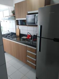 a kitchen with a stainless steel refrigerator and a microwave at Verano Praia Ponta Negra AP 1401 in Natal