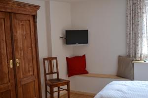 a bedroom with a red pillow and a chair at Gästehaus Alter Keller in Rothenburg ob der Tauber