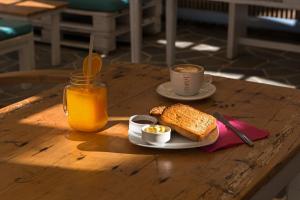 a table with a plate of bread and a cup of orange juice at Perigiali Rooms & Apartments Folegandros in Agali