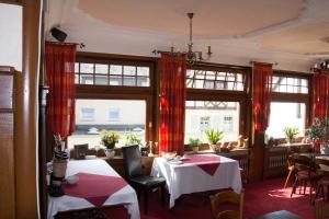 a restaurant with two tables and chairs and windows at Hotel Haupt in Kobern-Gondorf