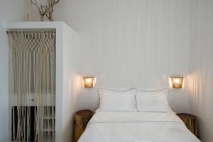 a white bedroom with a bed and two lamps at Perigiali Rooms & Apartments Folegandros in Agali