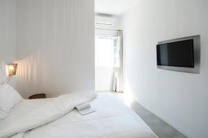 a white room with a bed and a flat screen tv at Perigiali Rooms & Apartments Folegandros in Agali