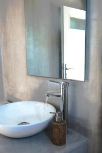 a bathroom with a white sink and a mirror at Perigiali Rooms & Apartments Folegandros in Agali