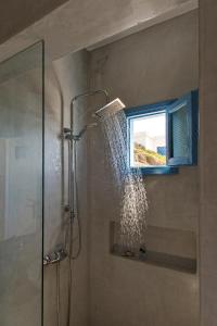 a shower with a window in a bathroom at Perigiali Rooms & Apartments Folegandros in Agali
