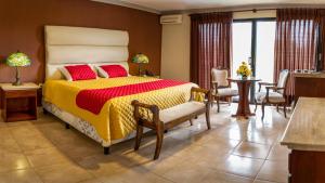 a bedroom with a bed with a yellow and red comforter at Hotel Los Ceibos in Tarija