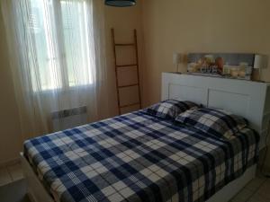 a bedroom with a bed with a blue and white checkered blanket at charmante villa individuelle proche de la mer in Bormes-les-Mimosas