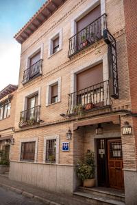 - un grand bâtiment en briques avec des balcons dans une rue dans l'établissement Hostal Tic-Tac, à Mocejón