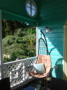 un fauteuil à bascule sur une terrasse couverte avec une fenêtre dans l'établissement Palm Cottage, à Castries